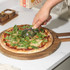 Stone-baked pizza with rocket on wooden board, overhead view