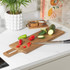 Kitchen scene with wooden chopping board, knife, sliced courgette and chillies.