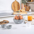 Electric egg cooker with two poaching trays and clear lid, kitchen countertop setting