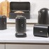 Black kitchen storage tins for salt, coffee, and bread, with metallic lettering.