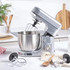 Silver stand mixer with bowl on countertop beside loaf of bread and cake