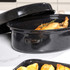 Black enamel roasting pan and lid in dishwasher, shown for cleaning suitability.