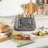 Close-up of grey toaster with two crumb trays partially open showing crumbs