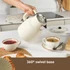 Cream electric kettle with chrome accents, switched on next to a tea cup