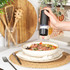 Black electric salt or pepper grinder in use over a plate of food