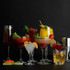 Assorted cocktails in various glasses with fruit and herb garnishes on black background