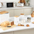 White and wood kitchen storage set with matching kettle, canisters, toaster, and microwave on worktop