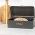 Black bread bin with gold lettering, open lid showing a loaf on kitchen worktop