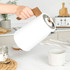 White and wood kitchen set with kettle, toaster, microwave, and storage canisters on worktop