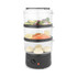 Three-tier electric food steamer with vegetables, salmon, and bao buns in clear baskets.