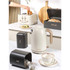 Cream electric kettle pouring hot water into grey mug, shown from side angle.