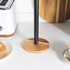Paper towel holder with black upright pole and round acacia wood base on kitchen counter