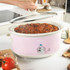 Pink Salter slow cooker on kitchen counter filled with cooked chilli, lid being lifted