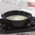 Eggs poaching in black tray inside Salter electric egg cooker, lid being lifted