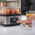 Egg boiler with digital display, poaching two eggs, hand lifting clear lid