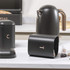 Matte black kitchen set with metal kettle, bread bin, tea and coffee canisters