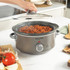 Salter grey slow cooker with chilli con carne being stirred, served with white rice.