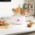 Pink Salter slow cooker with tomato stew, lid being lifted, kitchen counter setting