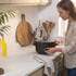 Black Salter slow cooker with stew cooking on kitchen counter, person adding greens