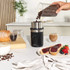 Black electric coffee grinder with stainless steel bowl, shown filled with coffee beans