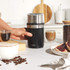 Black electric coffee grinder with stainless steel bowl, shown filled with coffee beans