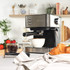 Black espresso coffee machine on kitchen counter, with cup, strawberries and croissants
