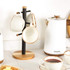 Set of cream ceramic mugs with brown rim on wooden stand, next to white kettle
