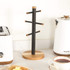 Cream ceramic mug with brown rim on wooden stand, hand reaching to hang mug, UK kitchen.