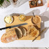 Sliced roast beef joint with garlic and herbs on a wooden board, chef's knife beside