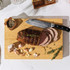 Sliced roast beef on wooden chopping board with garlic and fresh thyme
