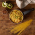 Cooked spaghetti with sliced spring onion and chilli flakes in a saucepan, with uncooked pasta.