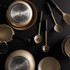 Gold non-stick cookware set with utensils on black background, shown from above