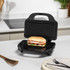 Black sandwich maker with toasted ciabatta sandwich in modern kitchen setting