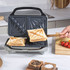 Grey waffle maker with two golden waffles on kitchen counter, lid open.