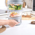 Electric food steamer with salmon and vegetables, dial being turned by hand