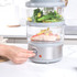 Set of Salter glass food containers with cooked rice, salmon, and steamed vegetables in kitchen.