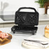 Black sandwich toaster with open lid on a kitchen counter