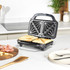 Black sandwich toaster with two toasted sandwiches in a modern kitchen