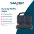 Black waffle maker with two golden waffles on kitchen worktop, hand lifting one waffle.