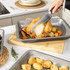 Roasting tin with cooked chicken and vegetables, hand carving a slice