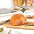 Digital cooking thermometer measuring roast ham temperature on kitchen counter