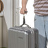 Hand using digital luggage scale to weigh suitcase with attached black strap