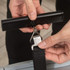 Close-up of hands attaching a black luggage strap to a suitcase using a metal clip