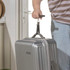 Close-up of hands attaching a black luggage strap to a suitcase using a metal clip