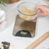 Digital kitchen scale in silver stored in a kitchen drawer beside wooden utensils