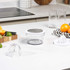 Multifunction citrus juicer and grater shown on kitchen worktop with fruits.