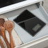 Black glass digital kitchen scale in drawer next to wooden utensils