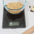 Black digital kitchen scale on worktop, shown with baking ingredients