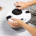 White salad spinner with black details shown in use on a kitchen worktop.