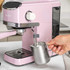 Pink espresso coffee machine on kitchen counter with coffee and croissants nearby